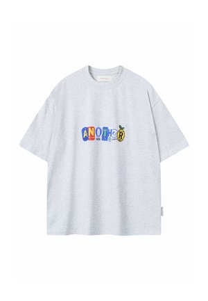 Maglietta a maniche corte grigio chiaro con lettere patch colorate che formano la scritta "ANOTHER" sul petto, stilizzate in diversi caratteri e forme.