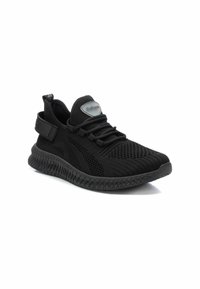 Zapatillas negras con parte superior de malla transpirable, suela de goma texturizada, cordones elásticos y un acento de logo reflectante en la lengüeta.