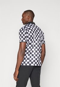 Black and white checkered polo shirt with a textured finish, short sleeves, and a black collar. Seen from the back.