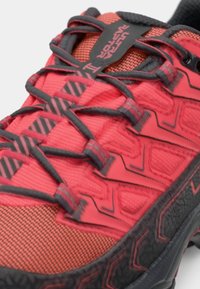 Κόκκινα αθλητικά παπούτσια με υφή στην επιφάνεια, μαύρες λεπτομέρειες και πολύπλοκο σύστημα κορδονιών με ανυψωμένη σόλα για πρόσφυση.