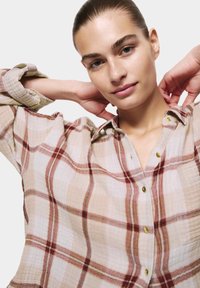 Camicia a quadri leggera in tonnellate di beige e rosso, con chiusura a bottoni sul davanti, maniche arrotolate e una vestibilità rilassata con tessuto testurizzato.