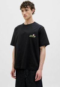 Černé bavlněné tričko s krátkým rukávem, které na hrudi nese barevný design "ATELIER ORIGINAL". Rovný střih s kulatým výstřihem.