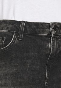 Černé džíny z denimu se sepranou texturou, designem na pět kapes a zapínáním na knoflík. Vlastnosti zahrnují viditelné švy a jemný lesk.