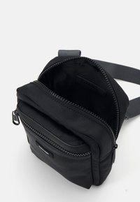 Borsa a spalla in tessuto nero con scomparto principale con zip e tasca frontale. Texture liscia, forma rettangolare e tracolla regolabile.