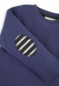 Námořnická modrá bavlněná mikina s kulatou pruhovanou nášivkou na lokti, která má kontrastní tmavé švy a klasický design s kulatým výstřihem.