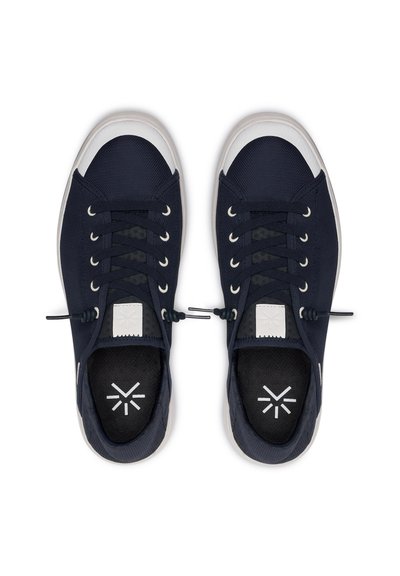 Námořnické modré tenisky s texturálním svrškem, bílou gumovou špičkou, plochými tkaničkami a vkládací podrážkou s potiskem loga. Obsahují minimalistické designové akcenty.