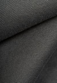 Tejido texturizado en tonos de negro y gris, con patrones acanalados, superficie suave y un acabado liso con ligeras variaciones en el tono.