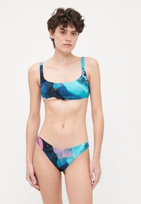 Bikini súprava s topom s štvorcovým výstrihom a nízkymi bokmi. S kvetinovými vzormi v modrej, tyrkysovej a ružovej farbe na tmavom pozadí.
