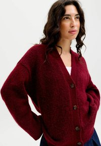 Burgunderfarbener Cardigan aus strukturiertem Stoff mit V-Ausschnitt, Knopfverschluss und lässiger Silhouette mit Taschen.