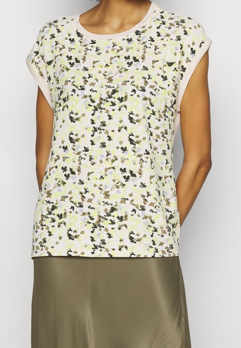Floral-patterned short-sleeve top in light pastel colors with a crew neckline and a relaxed fit. Soft, textured fabric with rolled sleeves.