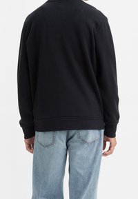 Svart sweatshirt med rund halsringning, långa ärmar och ribbad nederkant. Matchad med ljusblå denimjeans med bakfickor.