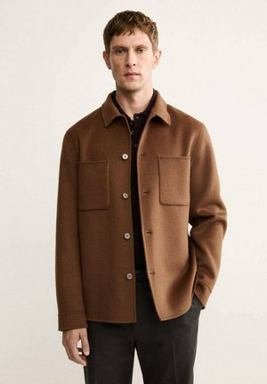 Chaqueta de mezcla de lana marrón con dos bolsillos frontales, cierre de botón y cuello. Textura suave, corte relajado y diseño minimalista.