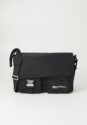 Czarna torba crossbody z regulowanym paskiem, przednią klapką, metalową klamrą, dwoma przednimi kieszeniami i naszywką z logo "Karl Lagerfeld Jeans".
