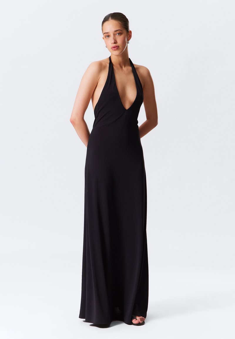 Vestido maxi negro con cuello halter, escote en V profundo, corsé ajustado y falda fluida. Fabricado en tejido elástico con una textura suave.