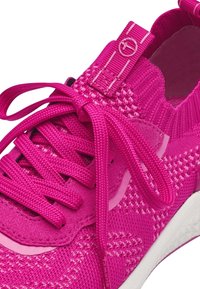 Scarpa da atletica rosa con tomaia a maglia con texture intrecciate, lacci piatti e linguetta posteriore. Suola bianca con tallone rinforzato.