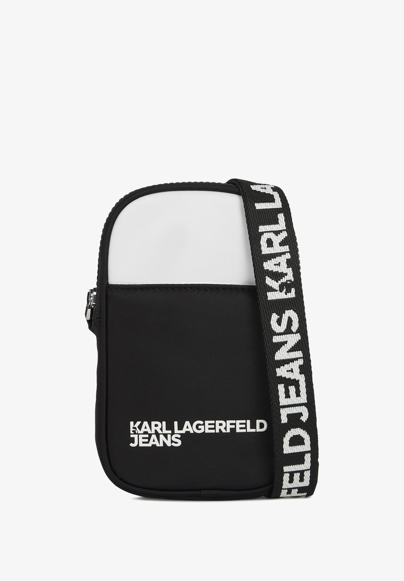 Juoda ir balta petinė kuprinė su lygiu audiniu. Yra baltas priekis, užtrauktuko uždarymas ir tekstūruota juostelė su prekės ženklu.