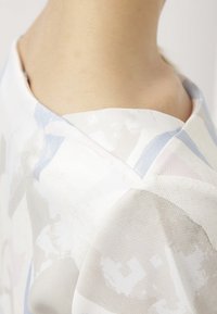Kortemou T-shirt met een witte stof met abstracte pastelpatronen, subtiele textuur en een v-vormige halslijn.
