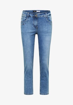 Vaaleansinisenä kapealahkeiset farkut, joissa edessä nappi, vetoketju, kaksi etutaskua ja haalistuneet pesuyksityiskohdat.