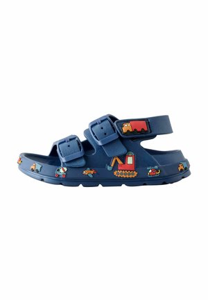 Navy blue children's sandal with two buckle straps, decorated with colorful construction and transport vehicle icons around the sole and strap.