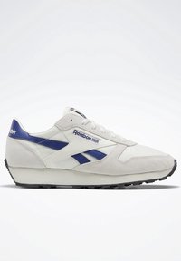 Vita och marinblå sportskor med ovandel i mocka och mesh, snörning och svart gummisula. Har Reebok-logotypen på sidan.