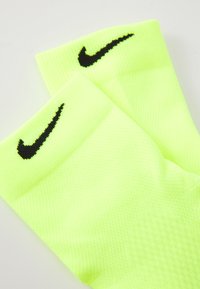 Bright neon yellow athletic socks with black Nike swoosh logos on the cuffs, displayed on a white background.