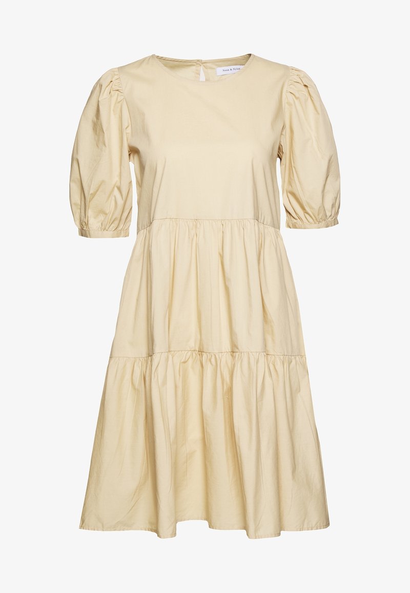 Robe beige jusqu’au genou avec manches courtes bouffantes, encolure ronde et volants froncés le long de la jupe pour une coupe ample.