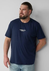 Granatowa bawełniana koszulka z krótkim rękawem, z białym haftowanym logo "s.Oliver Co." na klatce piersiowej, o prostym dekolcie w kształcie łodzi.