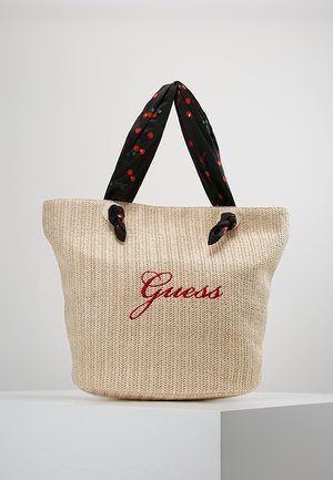 Beige gewebte Tragetasche mit rotem, gesticktem "Guess"-Logo und schwarzen Griffen mit Muster aus roten Kirschen.