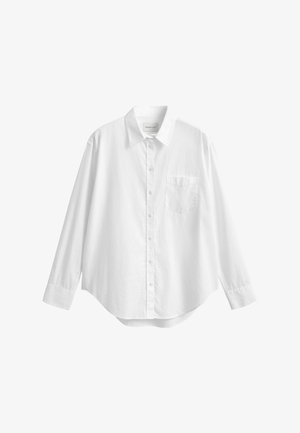 Chemise blanche à manches longues boutonnée avec col et poche poitrine avant, présentée sur un fond blanc uni.