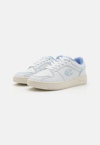 Hvid sneaker med lyseblå accenter, udstyret med en glat læderoverdel, perforeret tå, flade snørebånd og gummisål med tekstureret slidbane.
