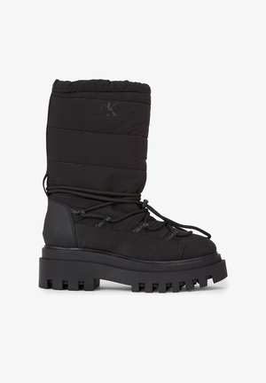 Botas negras impermeables con caña de tela acolchada, diseño de cordones, suela de goma texturizada, acentos de marca y una plataforma gruesa.