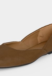 Καφέ γυναικείο επίπεδο παπούτσι με μυτερή μύτη, μαλακό επενδεδυμένο εσωτερικό και χαμηλή μαύρη σόλα.