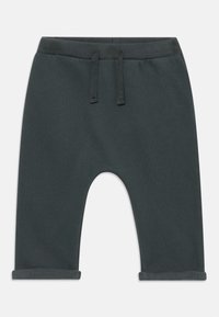 Pantalones de chándal gris oscuro con cintura elástica y cordón, que cuentan con un corte relajado y puños enrollados. Tejido suave y textura lisa.