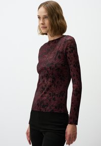 Langarm fitted top in bordeaux met een textuur met bloemenpatroon, voorzien van een ronde halslijn en een ribbelstructuur.