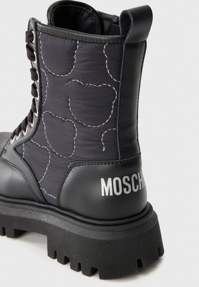 Botín negro con cordones, con un exterior de nylon acolchado y cuero, logotipo en el talón y una suela de goma gruesa y estriada.