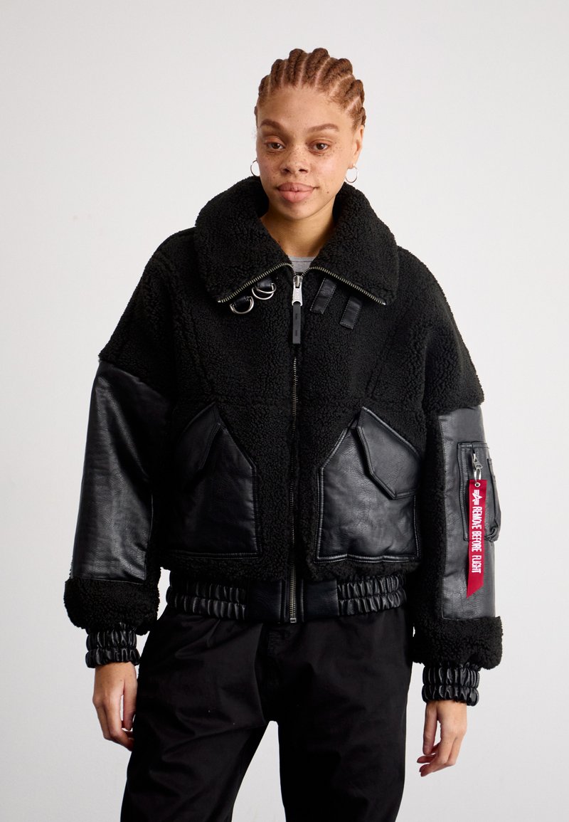 Zwarte cropped jas van fluffy schapenvacht materiaal met leren accenten. Heeft een brede kraag, elastische manchetten en ritszakken.