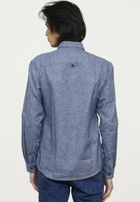 Langarmhemd in einem strukturierten blauen Stoff, mit einem button-down Kragen, einem Knopfdetail auf dem rug en contrasterende knopen op de manchet.