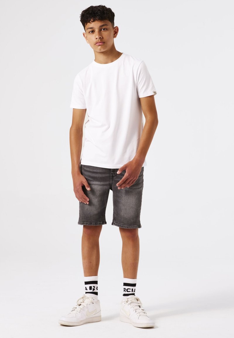 Witte korte mouwen t-shirt, grijze denim shorts, witte sneakers en zwart-wit gestreepte sokken. Minimalistisch ontwerp, casual pasvorm.