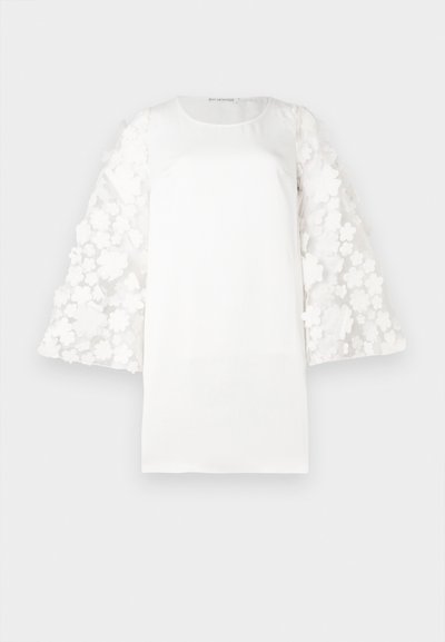 Top blanco con un cuerpo de tela suave y mangas abullonadas de patrón floral transparente hechas de material ligero. Cuello redondo simple.