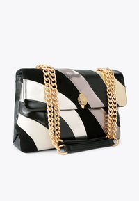 Black, white, and metallic silver striped faux leather handbag with a quilted texture, gold chain straps, and a decorative bird clasp.