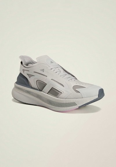 Chaussure de sport gris clair en mesh et matériaux synthétiques, talon prononcé, semelle texturée et accents de design géométrique en gris plus foncé.