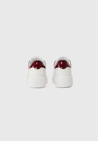 Witte sneakers met een glanzende bordeauxrode hielaccent, textuurzool en reliëfbranding op de hiel. Gladde, leerachtige materiaal.
