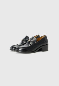 Sorte skinnloafers med lav blokkheel. Funksjoner inkluderer et dekorativt bånd over fronten og subtile sømdetaljer.