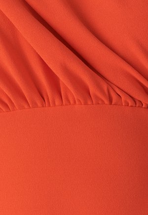 Tela fluida de color naranja con una textura suave. La parte superior tiene detalles fruncidos, que transitan a una sección inferior plana y sin estructura.