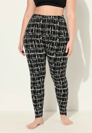 Leggings neri con un motivo a griglia bianca, caratterizzati da vita alta, texture liscia e design aderente, che terminano alla caviglia.