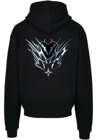 Mustat hupparit, joissa on rohkea hopeinen ja musta graafinen kuvio selkäpuolella, joka sisältää abstrakteja liekkimäisiä kuvioita ja keskeisen sydämen muotoilun.