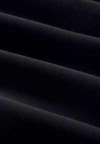 Tissu noir à texture lisse, présentant des plis subtils et une finition mate, sans motifs ni embellissements visibles.