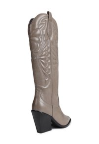 Botte de cowboy en cuir gris avec des coutures décoratives, bout pointu et un talon bloc de hauteur moyenne. Dispose d'un long chausson et de languettes de tirage.