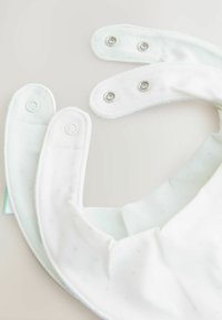 Ensemble de bavoirs blancs avec des bords arrondis, fermetures à pression, en coton doux, texture à motif subtil et accents vert clair.