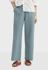 Pantalon bleu clair à jambes larges en tissu texturé avec des rayures verticales ; doté de poches latérales et d'une ceinture élastique.